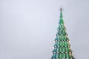 um fragmento de uma enorme árvore de natal com muitos enfeites, caixas de presente e lâmpadas luminosas. foto de um close de árvore de natal decorada com espaço de cópia