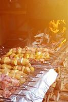 carne crua e batatas são plantadas em espetos de metal. o processo de cozinhar shish kebabs. comida de acampamento russa e ucraniana foto