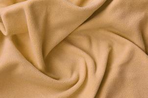 a manta de tecido de lã laranja peludo. um fundo de material de lã macia laranja claro com muitas dobras de relevo foto