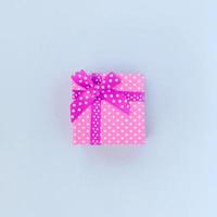 pequena caixa de presente roxa com fita encontra-se em um fundo violeta foto