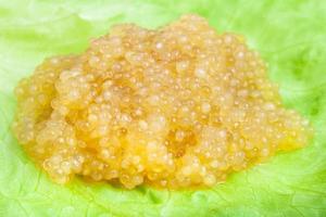 punhado de caviar salgado de peixe lúcio na folha verde foto
