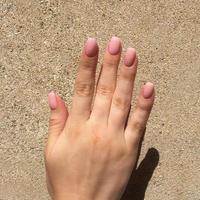 mãos femininas com manicure rosa elegante em fundo marrom foto