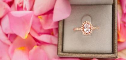 anel de diamante de casamento elegante na caixa de joias em fundo de pétala de rosa rosa linda close-up foto