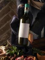 um tiro vertical de uma pessoa em um traje tradicional mostrando uma garrafa de vinho foto