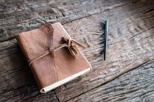 o livro de couro e a caneta sobre a mesa de madeira. foto