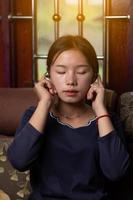 closeup tiro de uma menina asiática está ouvindo música com desfrutar e relaxar no sofá em casa do conceito de smartphone, entretenimento e descanso foto