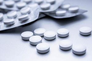 pílulas médicas brancas estão espalhadas na mesa cinza. foto