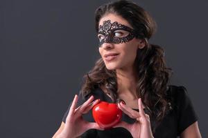 mulher usando máscara preta segurando formato de coração foto