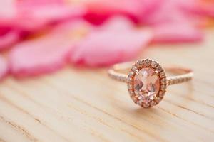 anel de diamante rosa de joias na mesa de madeira com fundo de pétalas de rosa bonito close-up foto