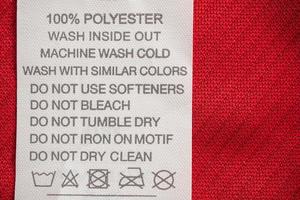 Instruções de lavagem de cuidados com a roupa branca etiqueta de roupas em camisa esportiva de poliéster de jersey vermelho foto