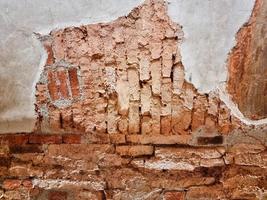 bloco de tijolo quadrado laranja áspero na parede de cimento texturizada e piso. forte rachadura de cimento interiores construção de casa foto