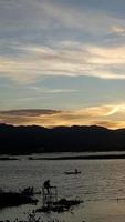 silhueta de um homem pescando à tarde. pôr do sol no lago limbo, indonésia foto