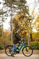 jovem com bicicleta elétrica no parque outono foto