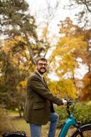 jovem com bicicleta elétrica no parque outono foto