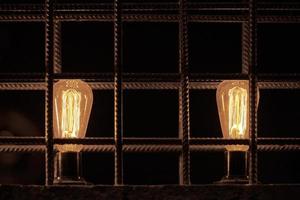 duas lâmpadas incandescentes decorativas dentro da divisória do loft da barra de aço reforçada foto