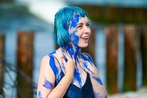 artista performática artística mulher de cabelos azuis em vestido manchado com tintas guache azul em seu corpo foto