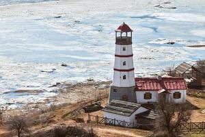 lindo farol vermelho branco com casas de serviços agrícolas em merzhanovo, rostov na região de don russo foto