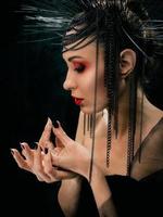 retrato de uma jovem mulher bonita como bruxa com lábios vermelhos e coroa preta sobre fundo escuro. beleza negra negra, conceito de halloween foto