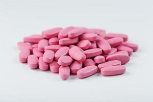 pílulas de vitamina rosa para mulheres em um fundo branco. foto