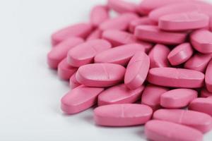 pílulas de vitamina rosa para mulheres em um fundo branco. foto