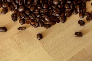 closeup de grãos de café torrado marrom em fundo de madeira foto