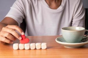 mão segurando corações de cubo de madeira dispostos em uma linha, simulado para criar símbolo ou logotipo, crescimento de negócios e conceito de gestão. foto