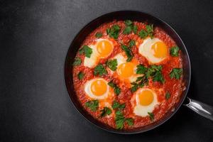 shakshuka, um prato com ovos fritos com molho de tomate, pimentão, alho, cebola, especiarias e ervas foto