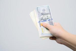 mão segurando o dinheiro dólar em fundo cinza. imagem de mão segurando notas de 100 dólares. dinheiro na mão. foto