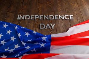 as palavras dia da independência colocadas na superfície de pranchas de madeira marrom com bandeira amassada dos estados unidos da américa foto
