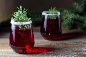 bebida vermelha de cranberry decorada com bagas de galhos de árvores de abeto e açúcar. vinho quente de natal foto