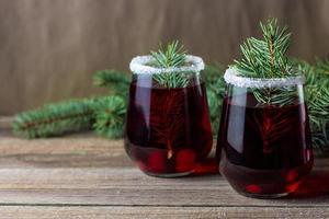 bebida vermelha de cranberry decorada com bagas de galhos de árvores de abeto e açúcar. vinho quente de natal foto