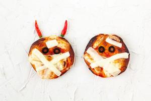 mini pizza como múmia com chifres para crianças com queijo, azeitonas e ketchup. comida louca e engraçada de halloween para crianças foto