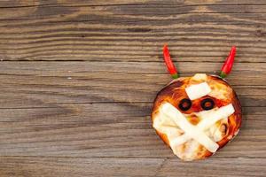 mini pizza como múmia com chifres para crianças com queijo, azeitonas e ketchup. comida louca e engraçada de halloween para crianças foto