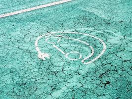 sinal de recarga de carro elétrico em um asfalto colorido azul foto