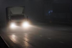 pequeno caminhão de van seca sem capuz movendo-se na estrada de neblina noturna foto