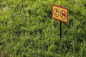 sinal amarelo com aplicação química sem cães no fundo do gramado verde - close-up com foco seletivo foto