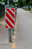 sinal listrado diagonal vermelho e branco na extremidade da cerca da estrada foto