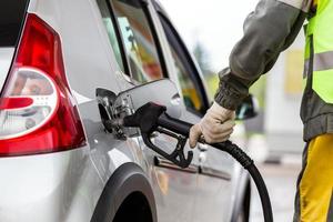 mão na luva de tecido de algodão branco reabastecimento de carro metálico cinza no posto de gasolina - close-up com foco seletivo foto