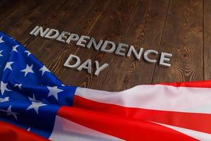 as palavras dia da independência colocadas na superfície de pranchas de madeira marrom com bandeira amassada dos estados unidos da américa foto