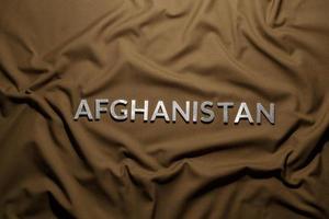 a palavra afeganistão colocada com letras de metal prateado em tecido de lona caqui amassado foto