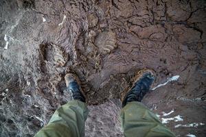 pernas em botas do exército em lama molhada closeup vista de cima para baixo com foco seletivo à luz do dia foto