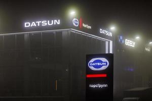 logotipo datsun no prédio da concessionária de carros na noite de neblina - datsun é uma marca de automóveis de propriedade da nissan motor company foto