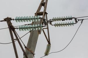 poste de linha de alta tensão com isoladores elétricos de vidro em fios foto