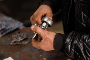 mãos sujas de técnico de carro caucasiano segurando chave e ferramenta de prata foto