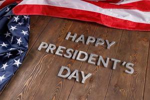 palavras feliz dia dos presidentes colocados com letras reais na placa de madeira perto de nós bandeira foto
