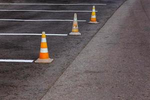 cones de estrada laranja em uma área de condução de asfalto com linhas brancas foto