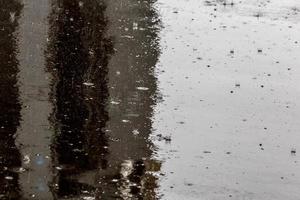 gotas de chuva no fundo de asfalto liso molhado brilhante com foco seletivo. foto