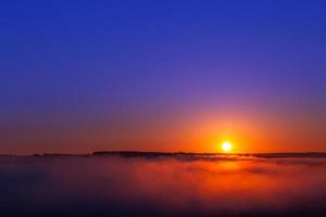 nascer do sol de verão azul dourado sobre nevoeiro sem nuvens em composição minimalista foto
