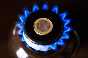 queimador de fogão a gás com uma moeda de euro colocada em cima, queimando gás natural com chama azul foto