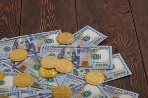moedas de bitcoin espalhadas sobre notas de papel de dólar americano em fundo de madeira foto